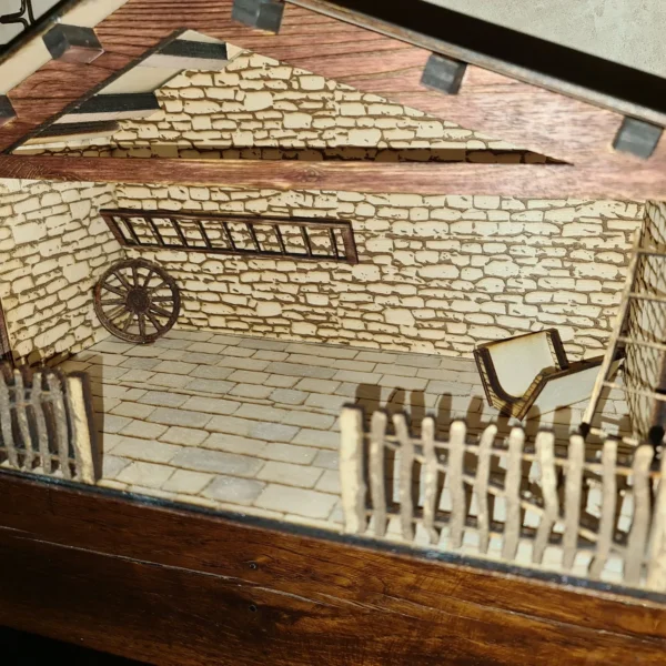 La Crèche de Noël est une écurie rustique miniature en pierre, avec une clôture en bois, une roue de chariot, un banc, un toit en bois incliné et un sol carrelé d'aspect pierre.