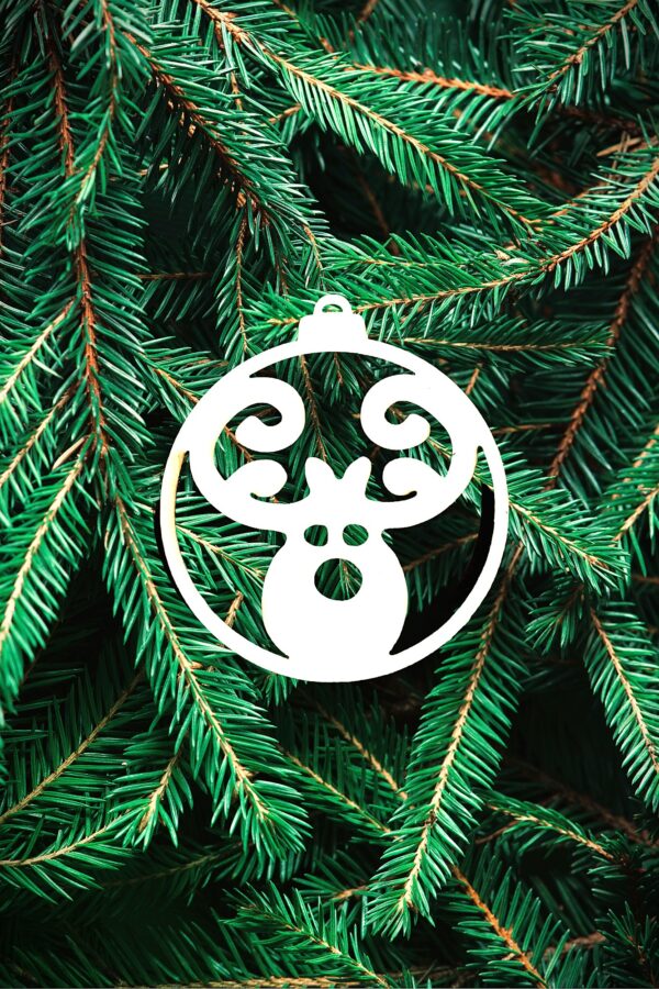 boule renne Une boule de noël blanche en forme de tête de renne est suspendu au milieu de branches de pin vertes et luxuriantes, créant une atmosphère de fête.